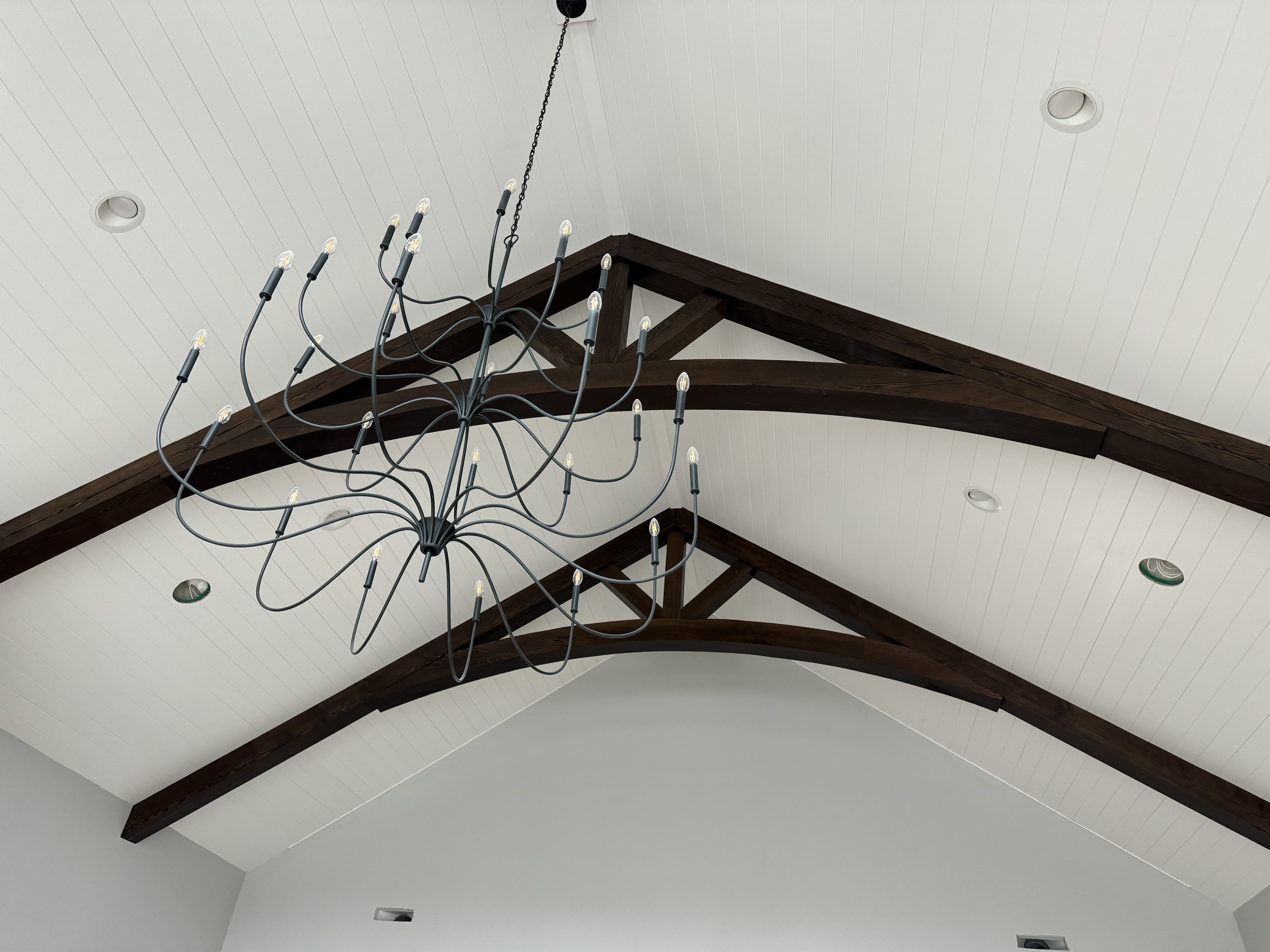 Interior timber trusses with chandelier on vaulted shiplap ceiling
